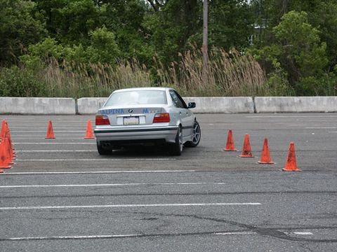 2001 Mercury Grand Marquis - A silver BMW M3 sedan is shown from the rear on an asphalt course marked with orange cones.