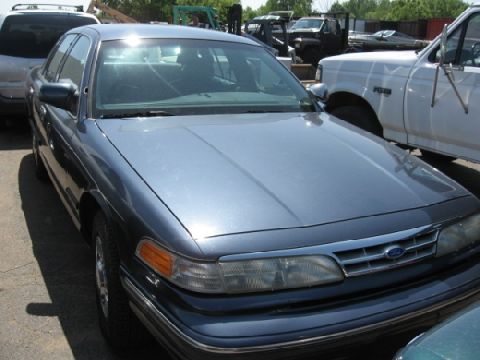 2003 Ford Crown Victoria - This blue Ford Crown Victoria is parked in an outdoor lot with other vehicles visible.