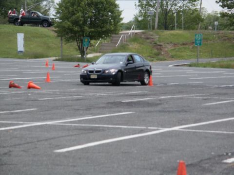 2001 Mercury Grand Marquis - A black BMW sedan is seen on a paved lot with orange cones, with a pickup truck in the background.