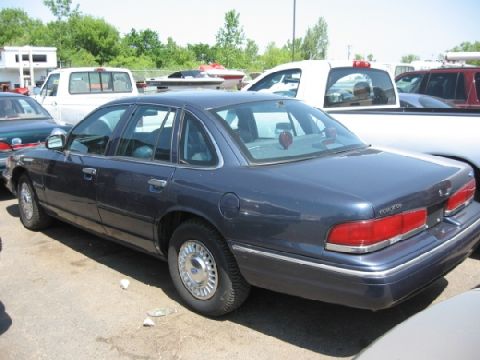 2003 Ford Crown Victoria - This 2003 Ford Crown Victoria is seen from the rear 3/4 angle in a parking lot with other vehicles.