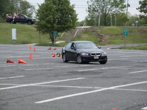 2001 Mercury Grand Marquis - A dark blue BMW sedan navigates a course marked by orange cones in a parking lot.