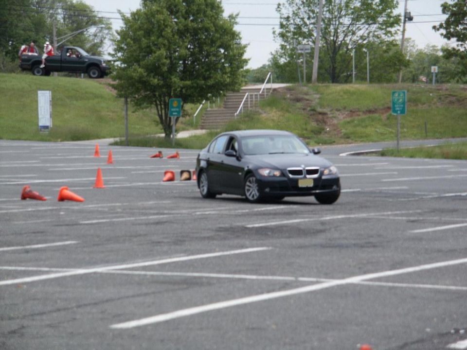 Dark blue BMW sedan on a paved lot with orange cones