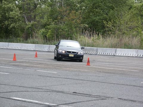 2001 Mercury Grand Marquis - A black BMW sedan is seen on an autocross course, maneuvering around orange cones on a paved track.