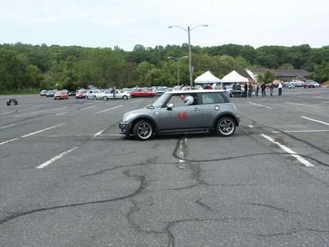 2001 Mercury Grand Marquis - A Mini Cooper participates in an autocross event on a paved lot with other vehicles and tents visible.