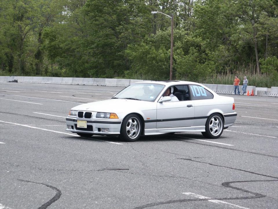 White BMW coupe with number 100 on rear window on asphalt track