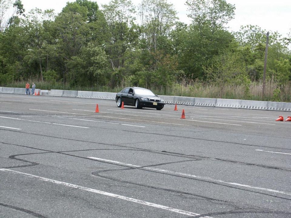 Black sedan navigating an autocross course with orange cones