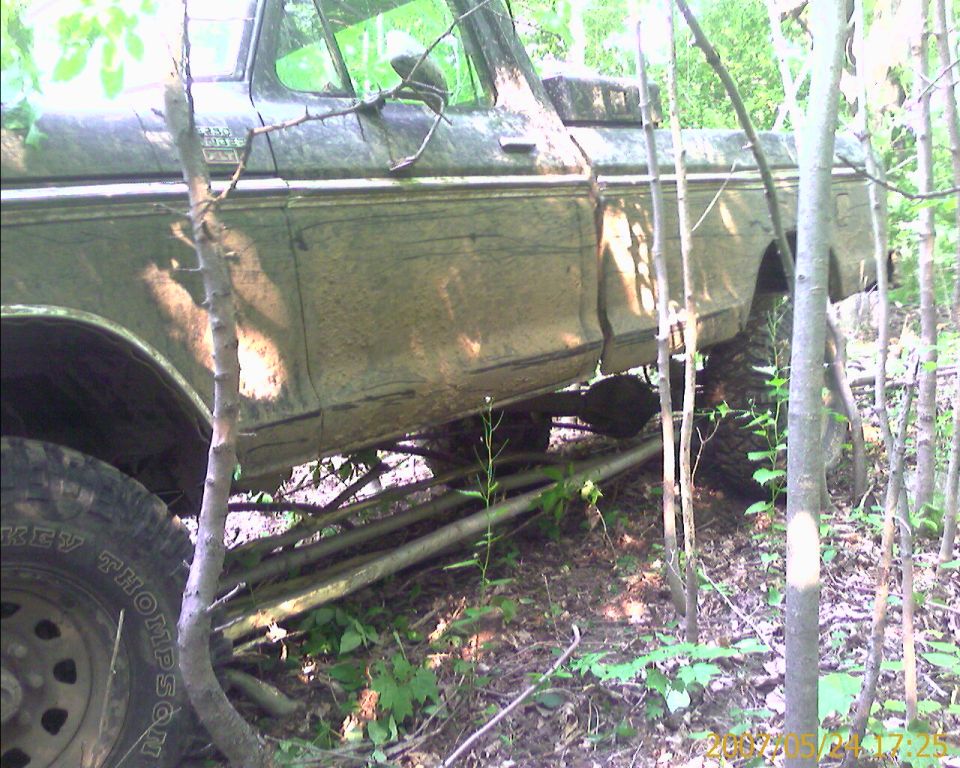 1979 Ford F-250 truck, side view, covered in mud, parked in woods