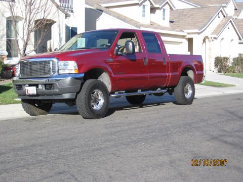 2004 Ford F-250 - This red pickup truck is parked on a residential street in front of houses.