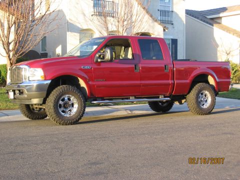 2004 Ford F-250 - A red 2004 Ford F-250 pickup truck is shown from the front three-quarter view on a sunny day.
