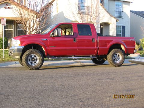 2004 Ford F-250 - A red 2004 Ford F-250 Super Duty pickup truck is parked on a residential street.