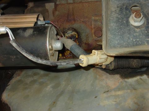 1994 Ford Bronco - Tight underhood shot of a starter motor solenoid with its wiring, showing a loomed harness lead running to a white two-pin connector and a…