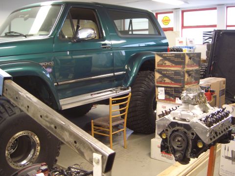 1996 Ford Bronco - Green 1996 Ford Bronco with aftermarket wheels and tires is shown indoors with engine components nearby.