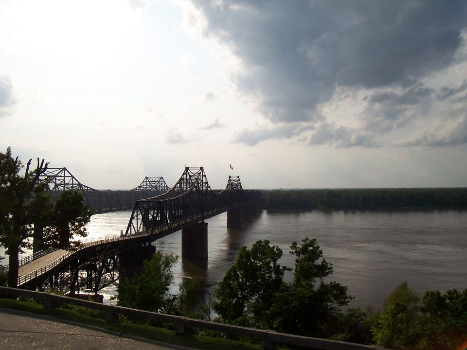 Bridge over a wide, muddy river under a cloudy sky