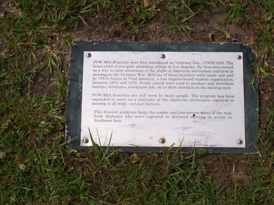 Metal memorial plaque describing POW-MIA bracelets, set in grass
