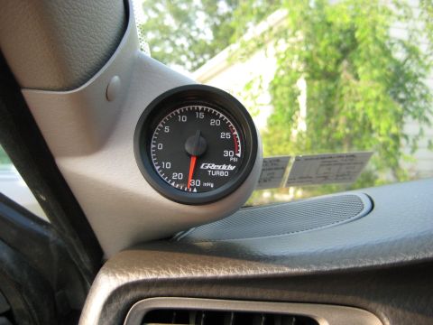 1993 Ford Probe - A GReddy turbo gauge is visible inside a vehicle's interior, with trees and sky seen through the windshield.