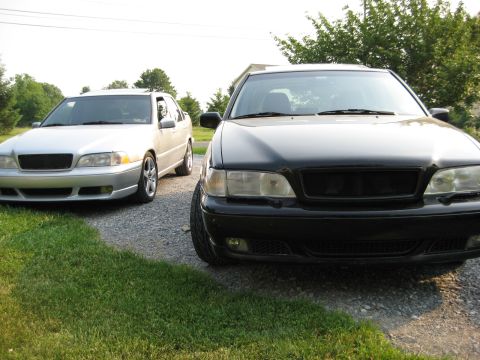 1993 Ford Probe - Two Volvo sedans are parked on a gravel driveway with grass in the foreground.
