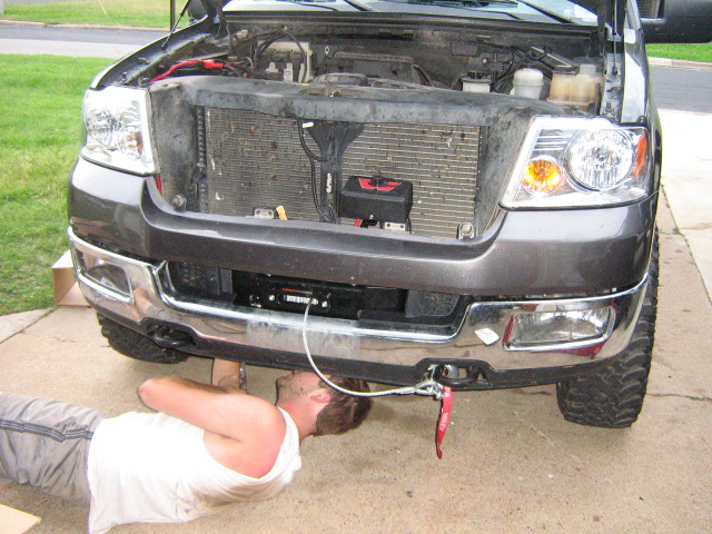 Gray Ford F-150 with hood open, showing engine and winch installed on front bumper