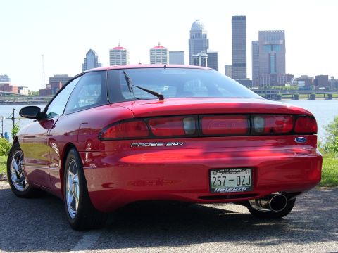 1991 Ford Probe - Rear view of a red 1991 Ford Probe GT parked with a city skyline in the background.
