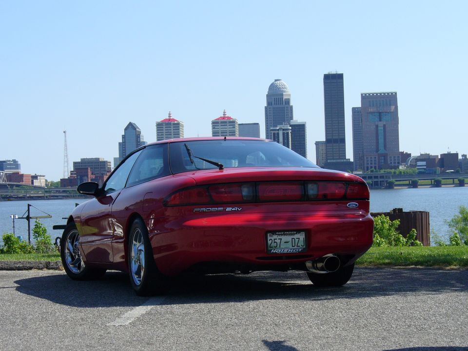 Red 1991 Ford Probe 24v parked with Louisville skyline in background