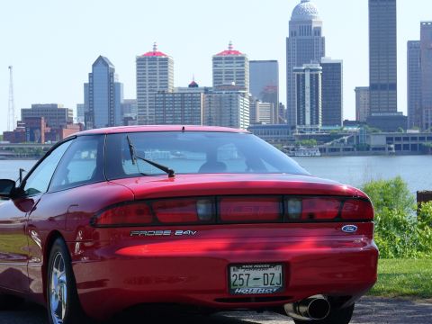 1991 Ford Probe - A red Ford Probe GT is parked with a city skyline and river in the background.