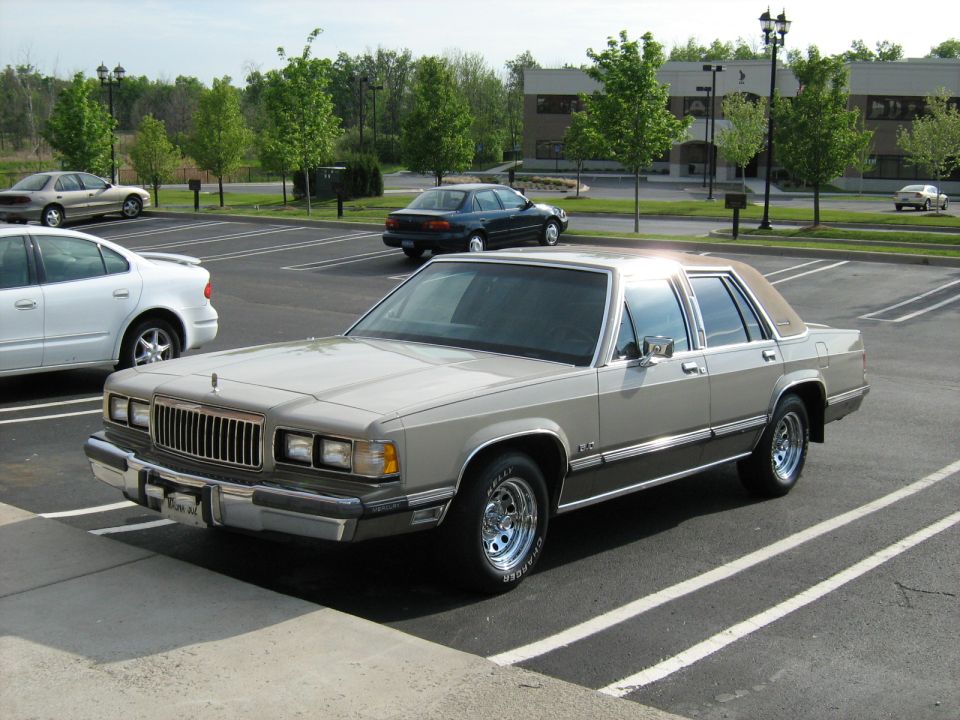 Champagne full-size Mercury sedan parked in a lot near office building