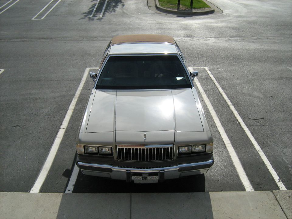 Overhead front view of a tan Mercury sedan in a parking space