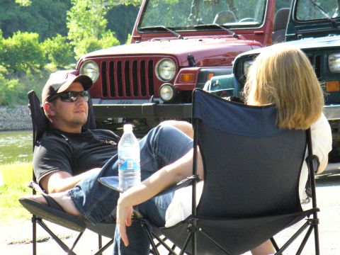1991 Ford Probe - Two people sit in chairs outdoors, with multiple Jeeps parked behind them on a sunny day.