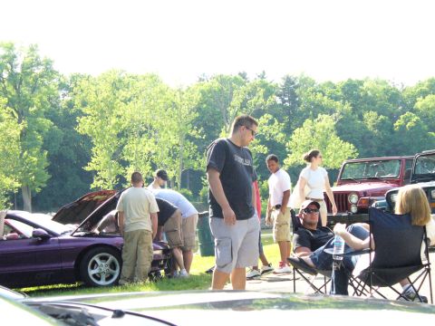 1991 Ford Probe - Several people are gathered around a purple sports car with its hood open at an outdoor event.