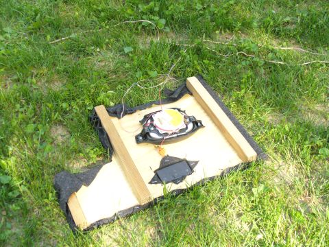 1991 Ford Probe - A car speaker is mounted on a wooden frame and placed on the grass.