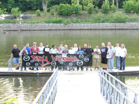 1991 Ford Probe - A group of people stand on a dock holding a banner that reads "MDY MAZDAS".
