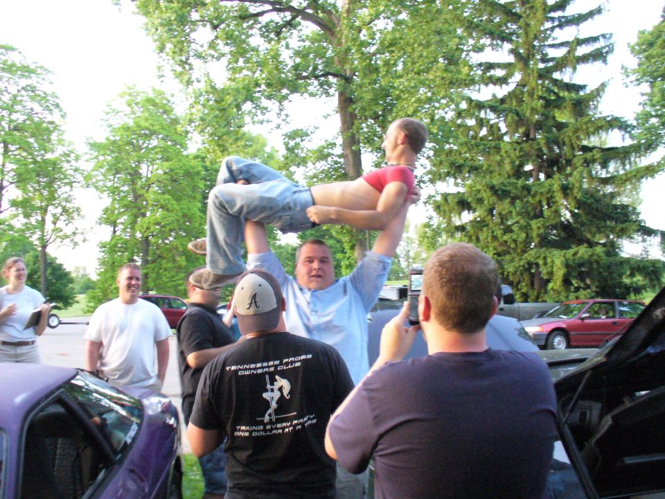 People lifting another person, Tennessee Probe Owners Club shirt visible