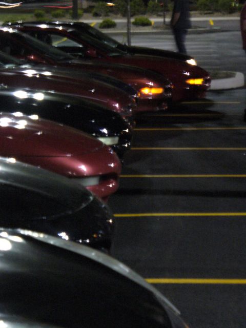 1991 Ford Probe - Multiple vehicles are parked in a lot at night, with yellow lines marking the parking spaces.