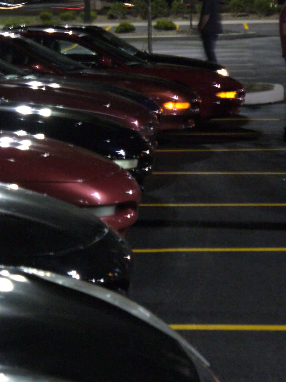Several cars parked side-by-side, one red, others black
