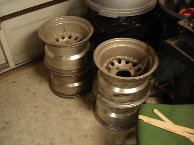Two stacks of aluminum wheels with five lug holes each, one with a cable inside, on a concrete floor