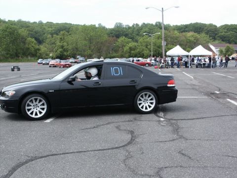 2001 Mercury Grand Marquis - A black sedan with racing numbers is parked at an event with other vehicles and tents visible.