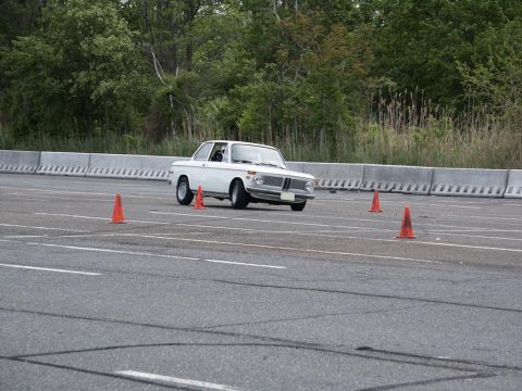 2001 Mercury Grand Marquis - A white BMW 2002 is seen on an autocross course, maneuvering around orange cones on a paved track.