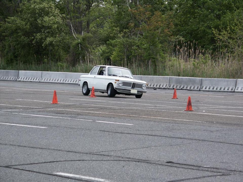 White 1973 BMW 2002 navigating an autocross course with orange cones