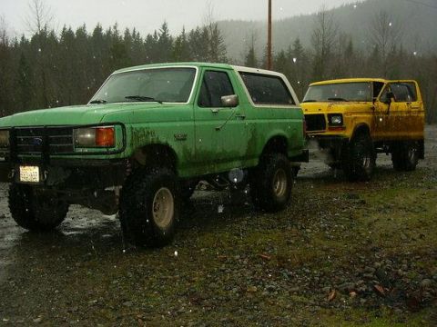 1978 Ford Bronco - Two Ford Broncos parked outdoors during a rain shower.