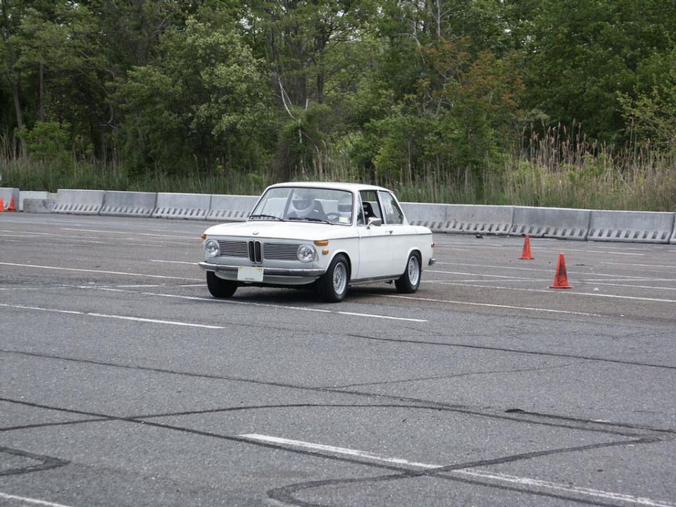 White 1970 BMW 2002 on asphalt with orange cones, front 3/4 view