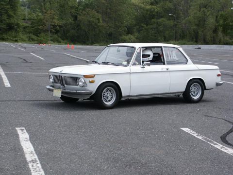 2001 Mercury Grand Marquis - White BMW 2002 on asphalt, driver wearing helmet and racing seat visible.