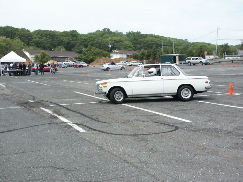 White coupe with racing stripes and driver in helmet, number 118 on door