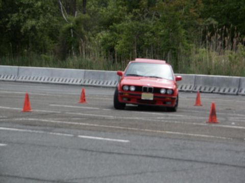2001 Mercury Grand Marquis - A red BMW E30 navigates a course marked by orange cones on a paved track.
