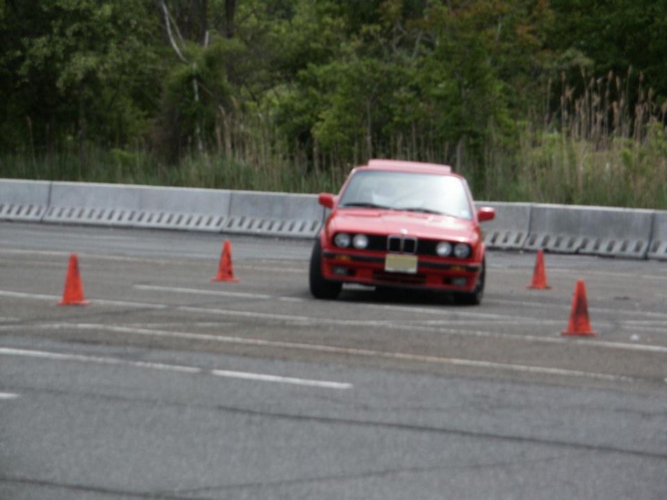 Red BMW E30 on a race track with orange cones