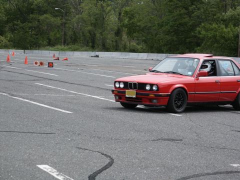 2001 Mercury Grand Marquis - A red BMW E30 sedan navigates a course marked by orange cones on a paved track.