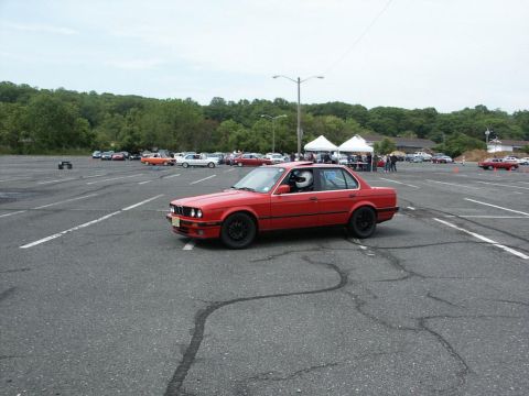 2001 Mercury Grand Marquis - A red sedan is parked on an asphalt lot, with other cars and tents in the background.