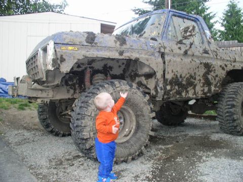 1979 Ford Bronco - Muddy 1978 Ford Bronco, modified for off-roading, stands with a small child nearby.