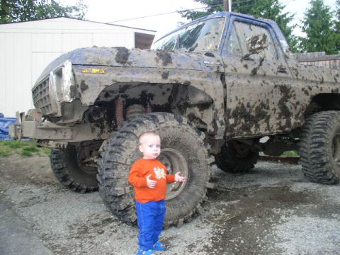 1979 Ford Bronco - A child stands next to a heavily mud-covered blue Ford Bronco, likely from the late 1970s.
