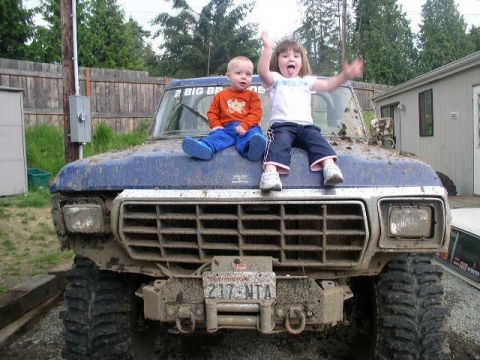 1979 Ford Bronco - Two children sit on the muddy hood of a blue 1978 Ford Bronco.
