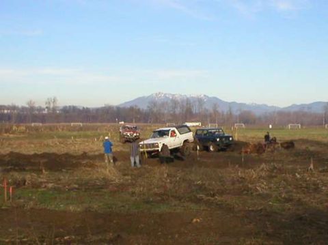 1979 Ford Bronco - A white 1979 Ford Bronco navigates a muddy off-road course with other vehicles present.