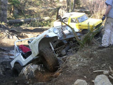 1979 Ford Bronco - Two off-road vehicles are stuck in the mud on a wooded trail.